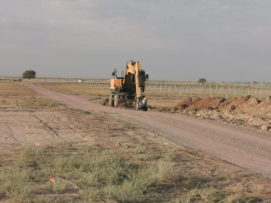 Excavator working beside long rows of freshly driven piles stretching to the horizon in Kazakhstan