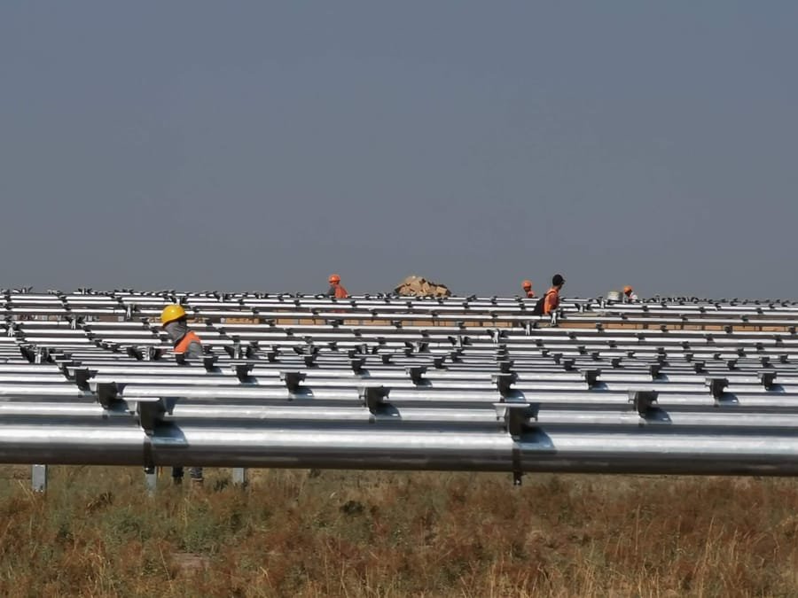 Workers installing torque tubes on mounting structure at a solar site in Kazakhstan