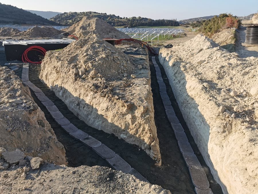 Wide cable trench with reels of cable beside a partially completed array in Cyprus