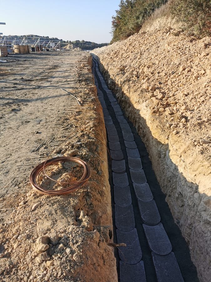 Coiled earthing cable beside an open duct trench on a solar site in Cyprus